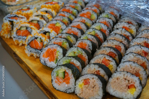 Delicious various types of Sushi rolls slices in bunch vegetarian with avocado, salmon, bacon, egg, carrot, cucumber, sesame seeds, been tuna red capsicum Japanese food traditional Asian cuisine
