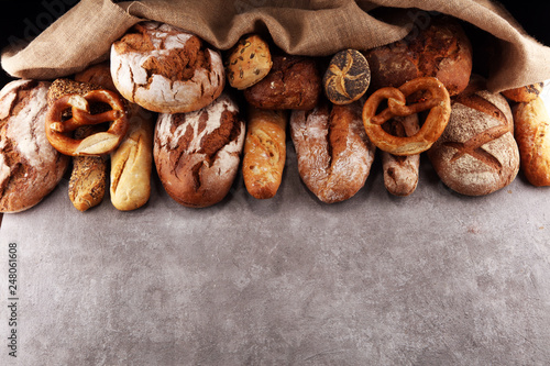 Assortment of baked bread and bread rolls on stone table background