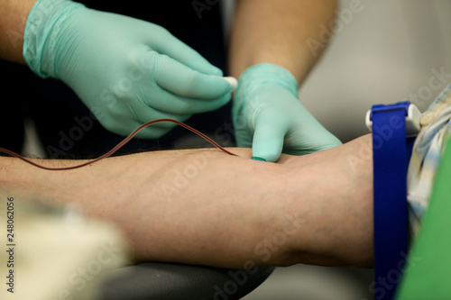 Details with the hands of a doctor taking blood from the vein of a patient with a catheter
