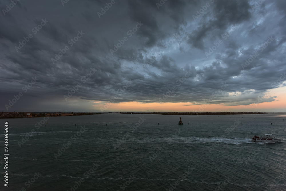 Boat sailing in front of Sant'Andrea island in the Venice lagoon during a thunderstorm
