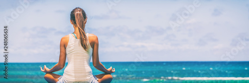 Yoga meditation wellness woman meditating on morning sunrise beach background in peace and zen positive attitude panoramic banner. Active sport and fitness lifestyle image.