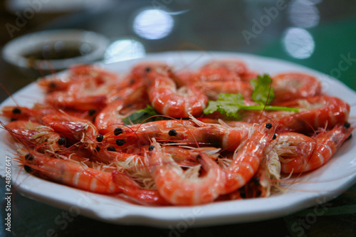 Boiled red shrimp served on a white dish with blue trim.