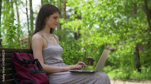 young girl working with notebook on a bench in the park