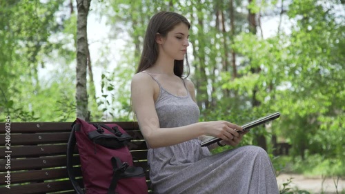 young girl working with notebook on a bench in the park