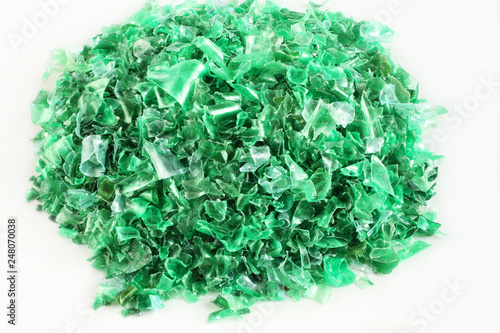 Small pieces of cut green plastic bottles on white paper