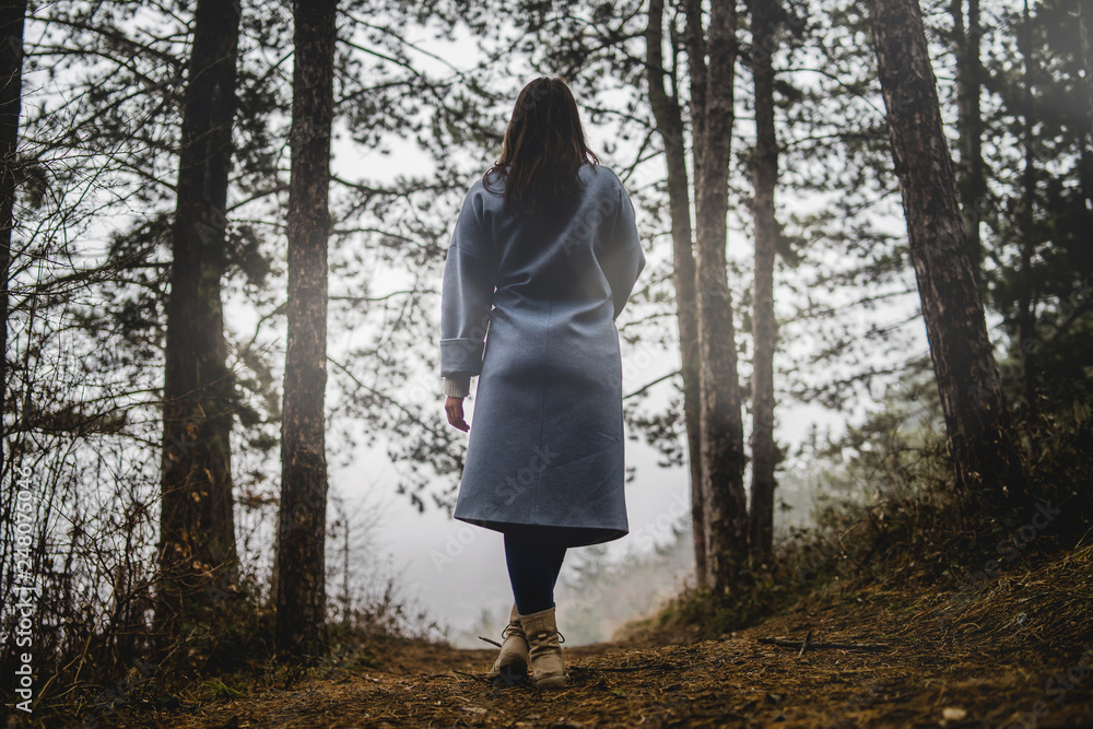 Back View of Young Woman Standing On Path In Forest between the woods Back View of Young Woman Standing On Path In Forest between the woods