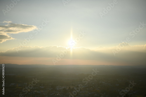 pre-sunset sunlight in the form of a bright star over the town to the mountains © Andrey