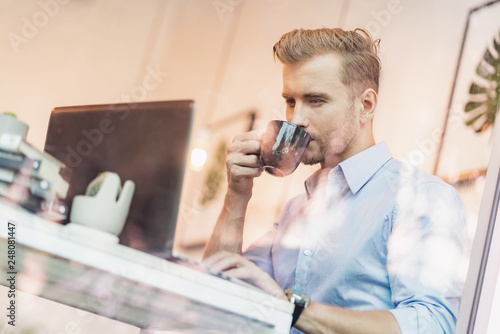 smart handsome caucasian businessman freelance working with laptop and enjoy coffee by big window in coffee shop