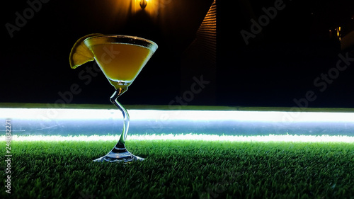 Low angle closeup of gourmet old fashion craft cocktail of sweet bourbon whiskey drink garnished by orange peel on grass dark background