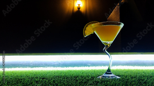 Low angle closeup of gourmet old fashion craft cocktail of sweet bourbon whiskey drink garnished by orange peel on grass dark background
