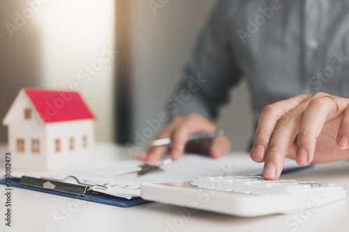 Home agents are using a calculator to calculate the loan period each month for the customer.