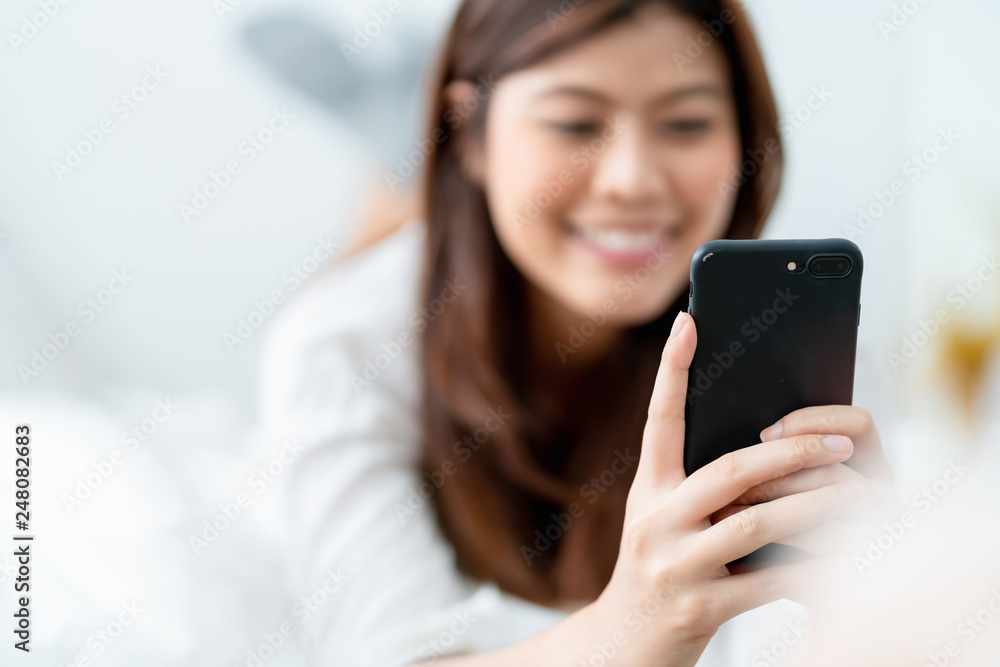 beautiful white shirt asian woman enjoy conversation hand hold smartphone on white bed holiday lifestyle