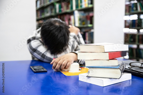 Foto Close up books burry Overworked male  student sleeping on the desk on his notes  at the library