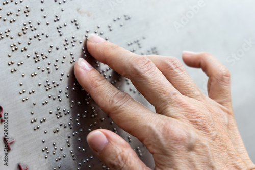Finger reading braille tactile on public park message board