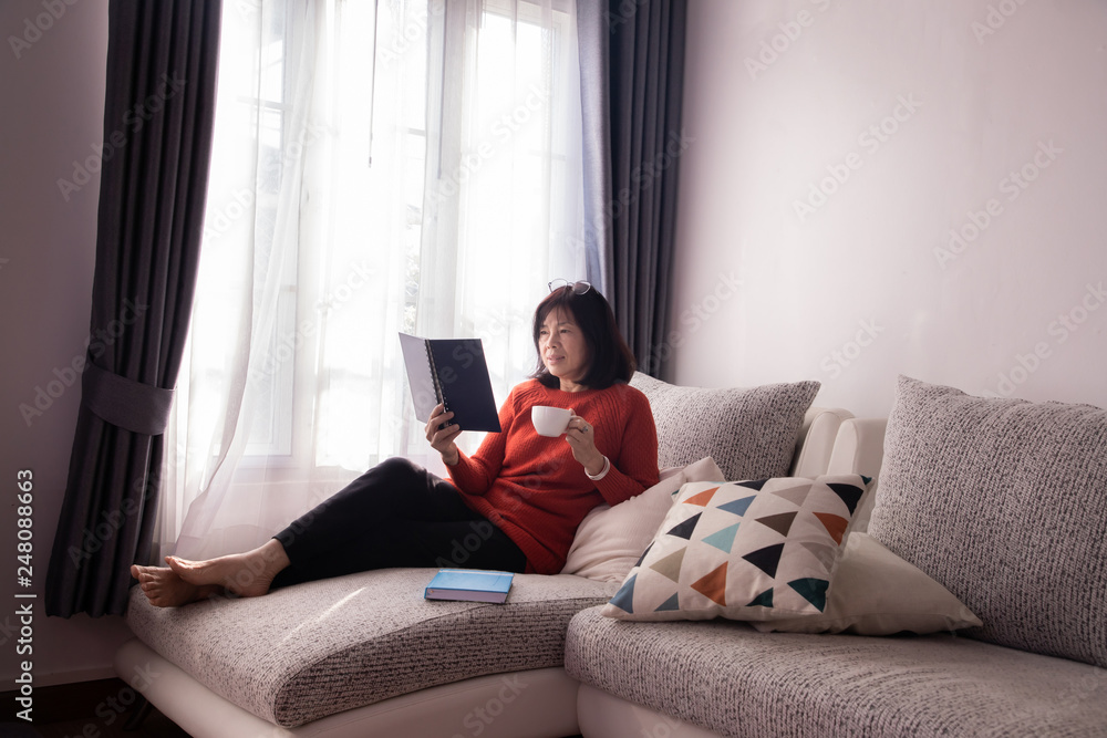 Beautiful girl at home sitting on the couch, reading a magazine and having a coffee break. Beautiful girl at home sitting on the couch, reading a magazine and having a coffee break.