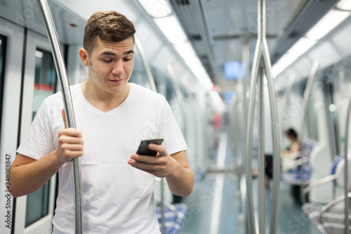 Man using phone in underground carriage