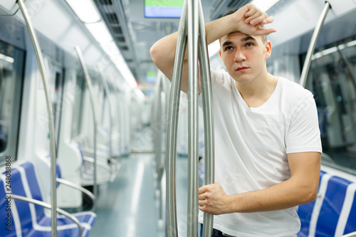 Exhausted passenger near handrail in subway