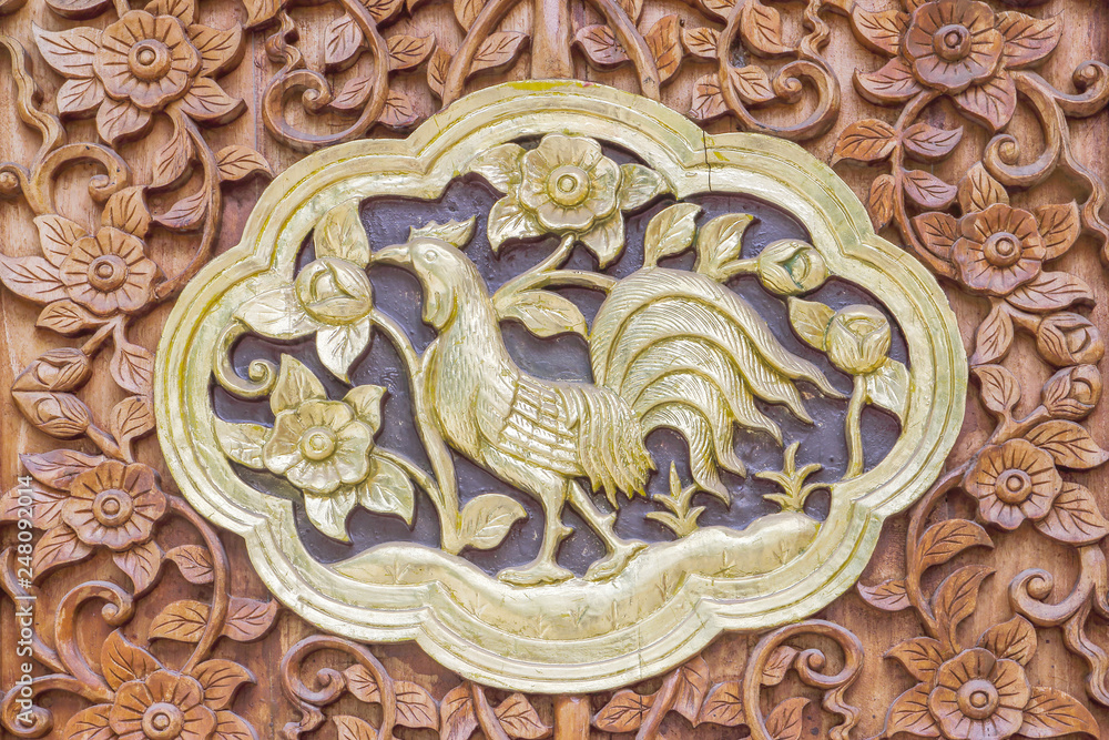 Traditional Thai style wood carving cock of 12 Zodiac,on the wall of temple in Thailand