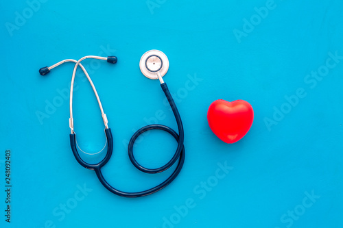 Heart health, health care concept. Stethoscope near rubber heart on blue background top view space for text