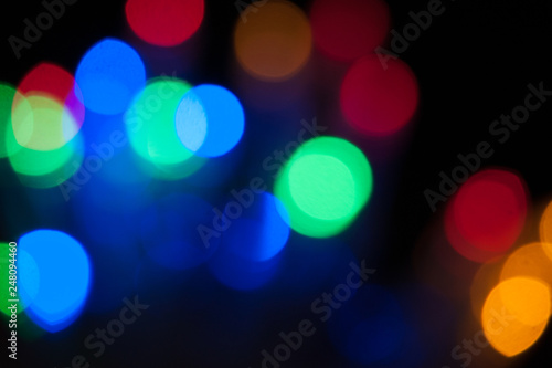 Blurred background, bright colored light bulbs, lights, the light from the garland. © Olga