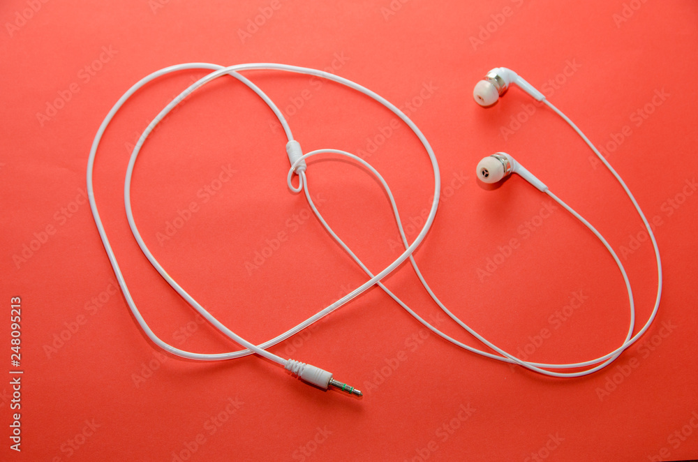 Beautiful modern, digital ,plastic ,vacuum, white headphones with wires for listening to music on a purple pink background Beautiful modern, digital ,plastic ,vacuum, white headphones with wires for listening to music on a purple pink background