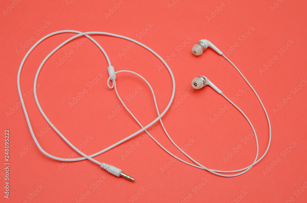 Beautiful modern, digital ,plastic ,vacuum, white headphones with wires for listening to music on a purple pink background Beautiful modern, digital ,plastic ,vacuum, white headphones with wires for listening to music on a purple pink background