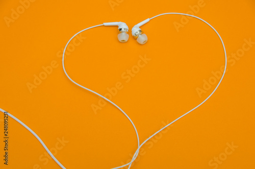 Beautiful modern, digital ,plastic ,vacuum, white headphones with wires for listening to music on a purple pink background