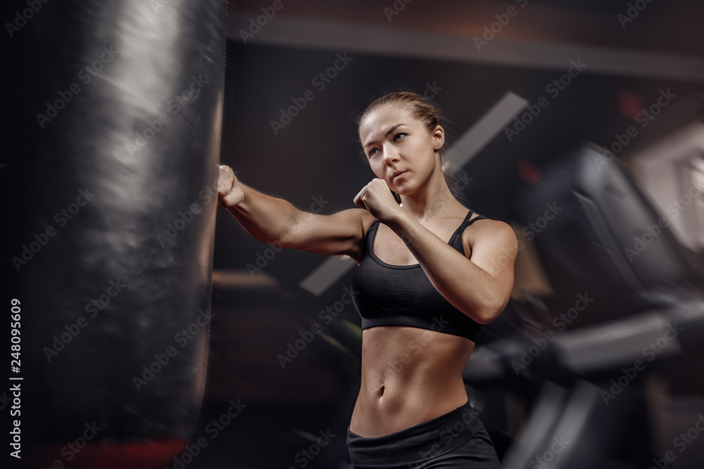 Fighter girl boxer punches pear fist, hair in motion. Fitness concept
