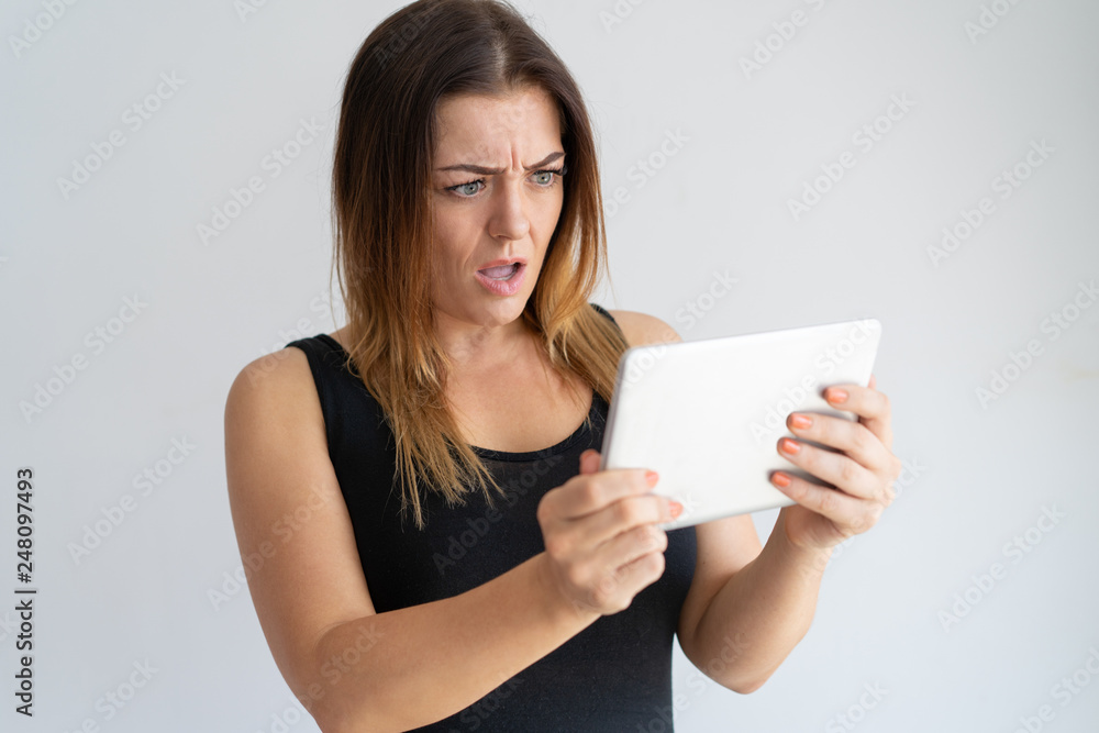Worried woman looking at tablet screen Worried woman looking at tablet screen