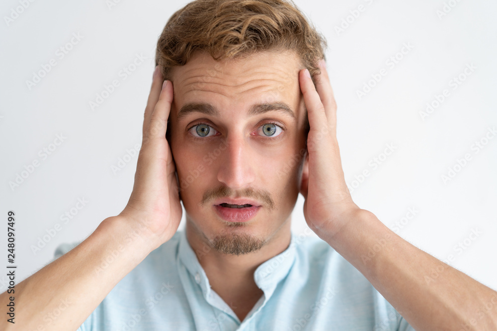 Worried young man looking at camera and touching head Worried young man looking at camera and touching head