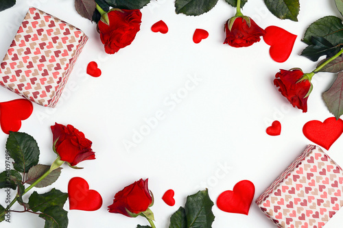Romantic frame of gifts, rose flowers and decorative hearts on white background. Place for text, top down composition.