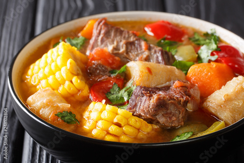 Latin American Sancocho thick meat soup with vegetables close-up on a plate on the table. horizontal photo