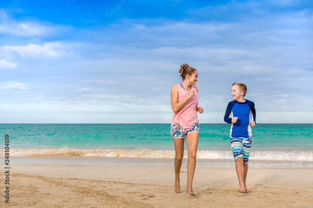 Smiling women and boy running together on a beautiful beach on vacation. Idyllic photo of a family beach holiday. Happy candid people in a scenic setting