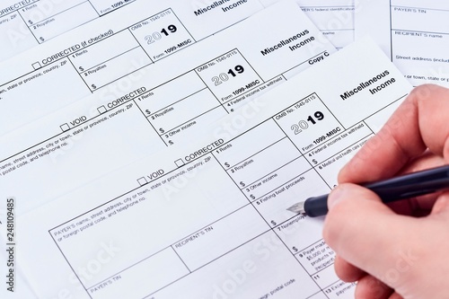 Tax reporting. Human fills out the 1099-misc tax form on background other forms