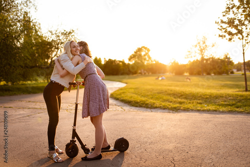 Young women embrace each other outside