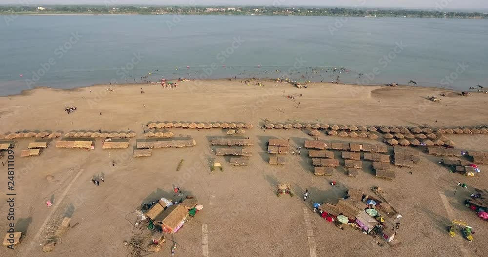 aerial drone shot : fly up revealing straw huts and wooden bungalows spread over sand beach aerial drone shot : fly up revealing straw huts and wooden bungalows spread over sand beach
