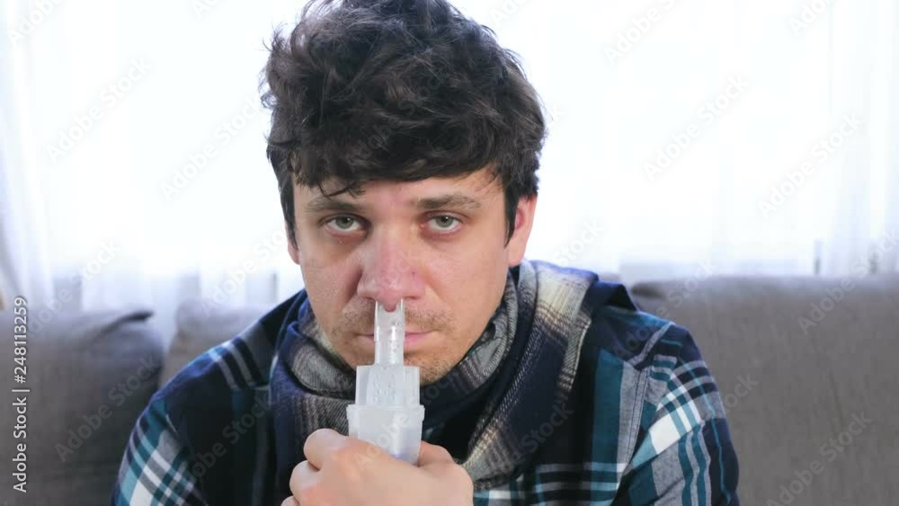 Sick man inhaling through inhaler nozzle for nose. Close-up face, front view. Use nebulizer and inhaler for the treatment. Sick man inhaling through inhaler nozzle for nose. Close-up face, front view. Use nebulizer and inhaler for the treatment.