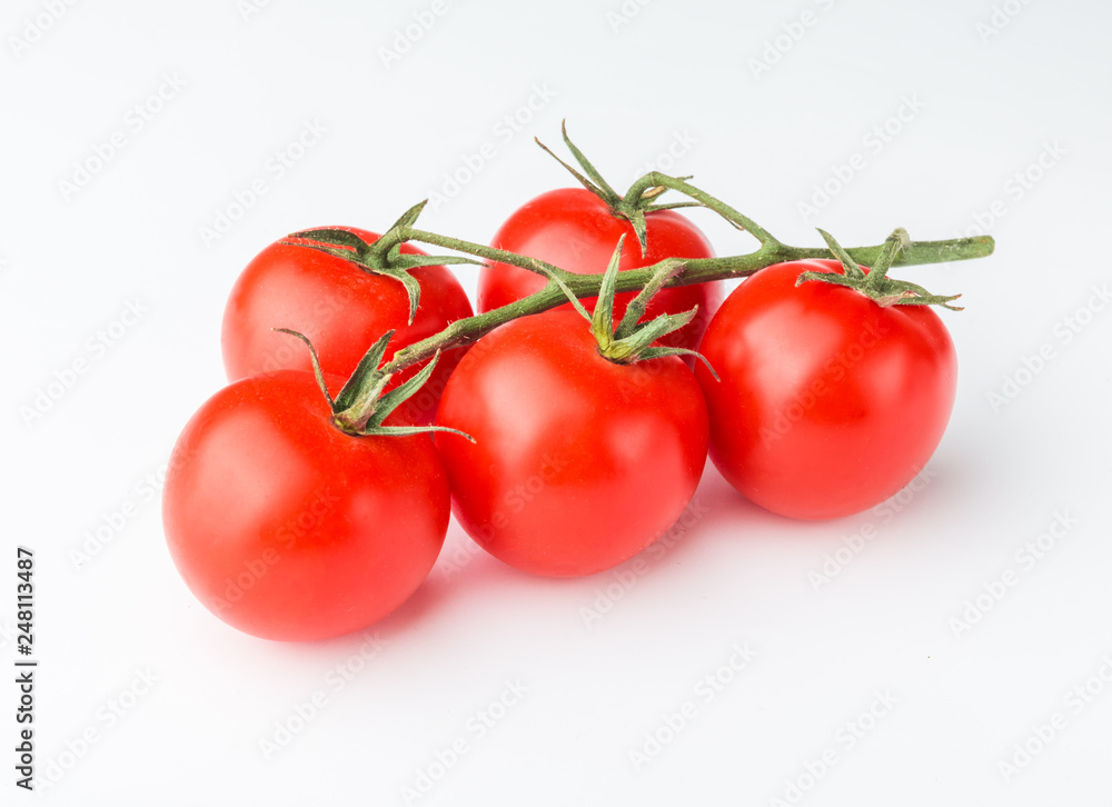 A branch of cherry tomato lies on a white surface. A branch of cherry tomato lies on a white surface.