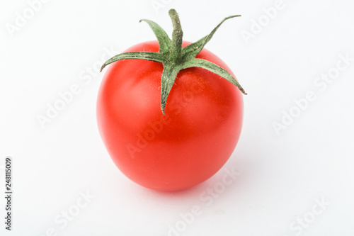 One cherry tomato lies on a white surface.