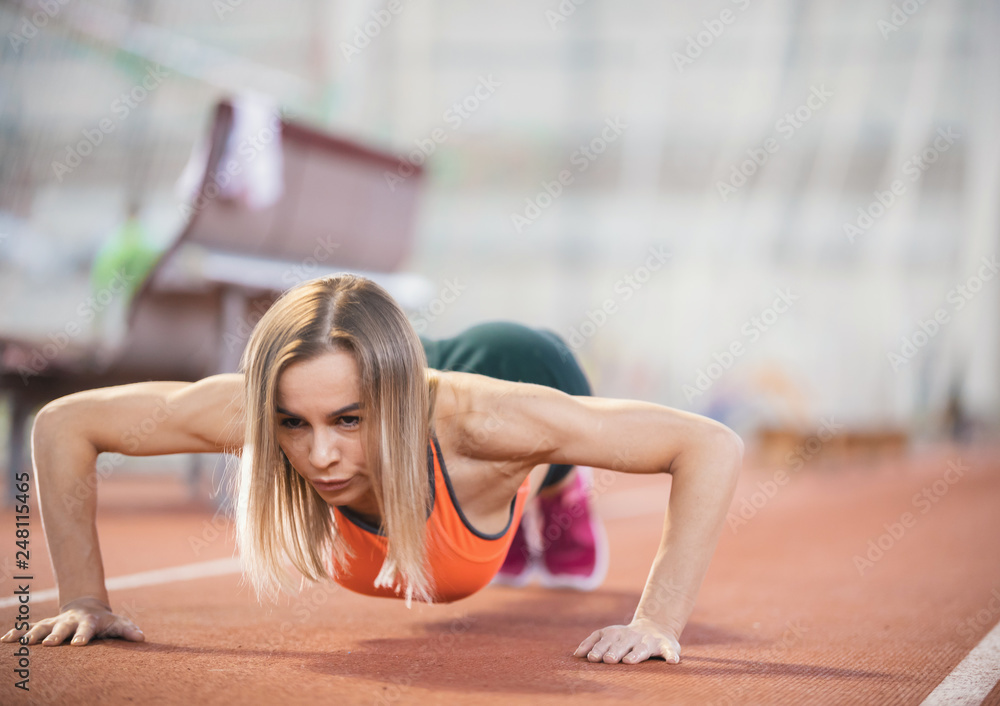 Fototapeta premium Young fit athletic woman in sports clothes doing push ups