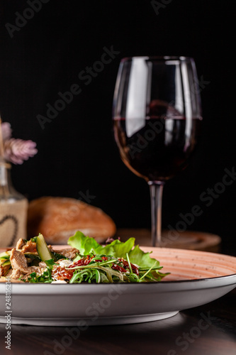 European Italian cuisine. Warm salad of veal, fried arugula, cucumber, mix lettuce, dried tomatoes, sweet peppers and cheese dorblu. Red wine.  background image. copy space