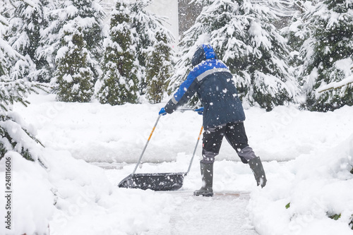 Man removing snow from the sidewalk after snowstorm. © Aleksey 159