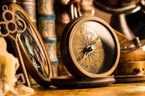 Antique compass on the background of a candle with a key and books. Vintage style. 1565 old map of the year.
