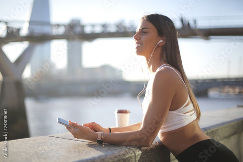 Photography Beautiful girl listening music with earphones, standing in the street, along the