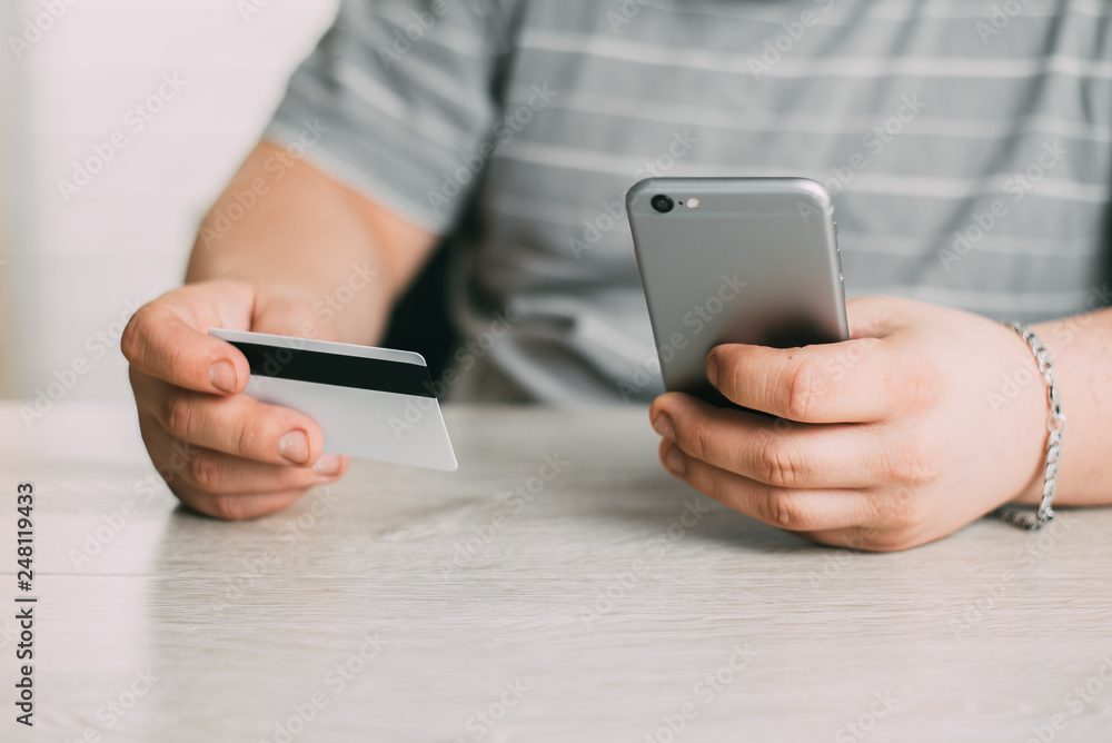 Cropped picture of man with credit card white pattern and phone Cropped picture of man with credit card white pattern and phone