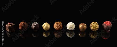 Set of fine chocolate candies White, dark and milk chocolate on black background with reflection