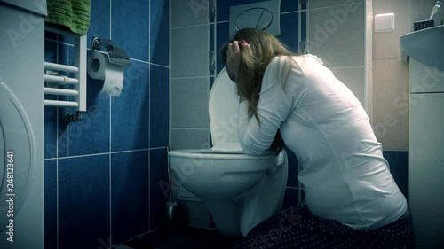 Young woman vomiting in bathroom wc - morning sickness during pregnancy