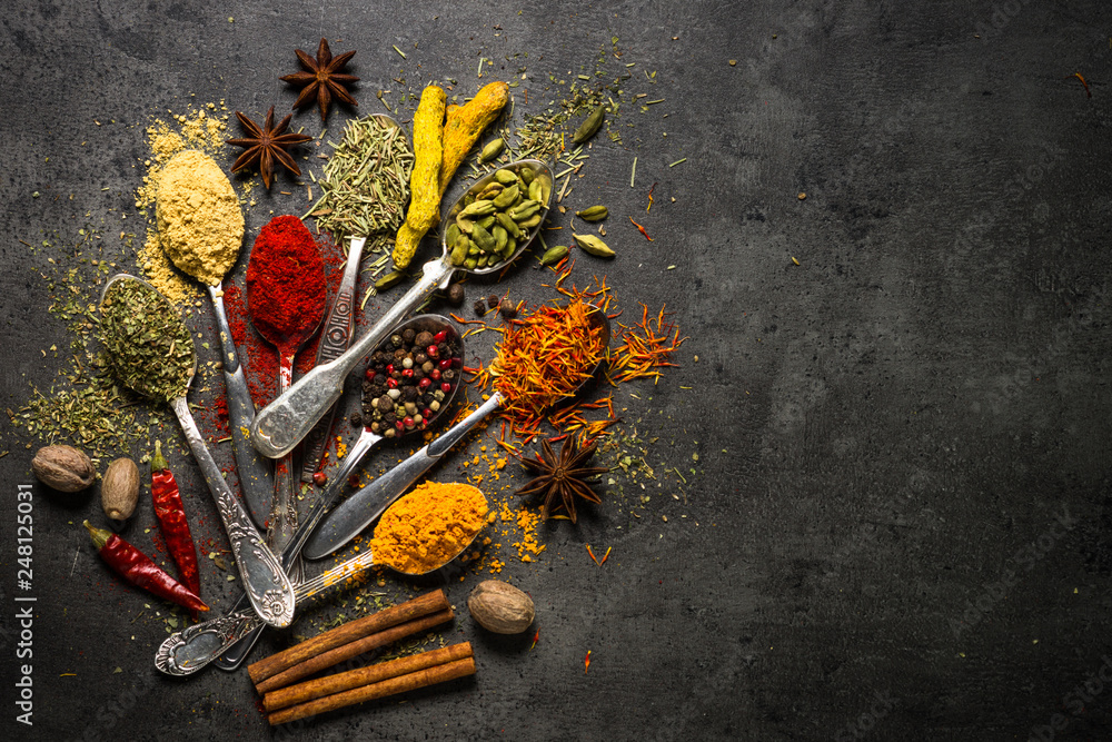 Set of various spices on black stone background.