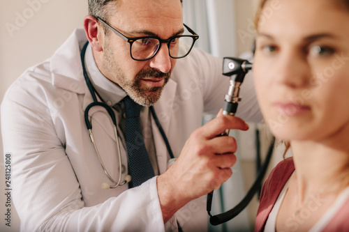 Cuadro en lienzo ENT doctor checking ear with otoscope of woman patient