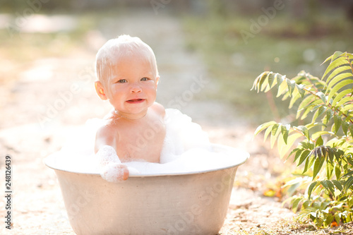 Funny baby take bath outdoors closeup. Looking at camera. Summer time. photo